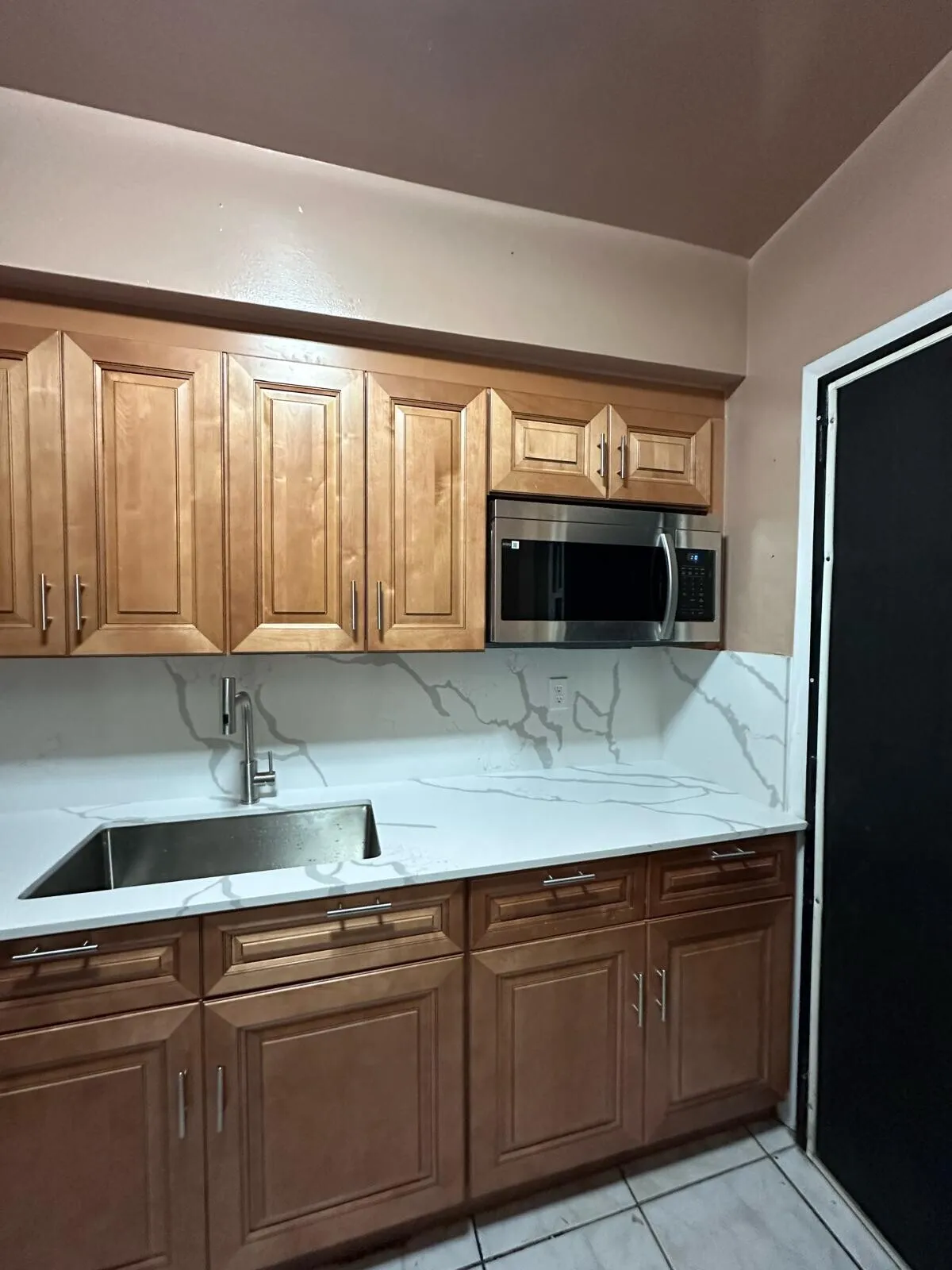 Remodeled kitchen with quartz counters and a marble-look backsplash, by MGS