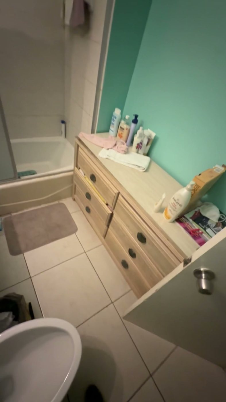 Before: the original bathroom, teal walls, white tile, a tub and a wood vanity.