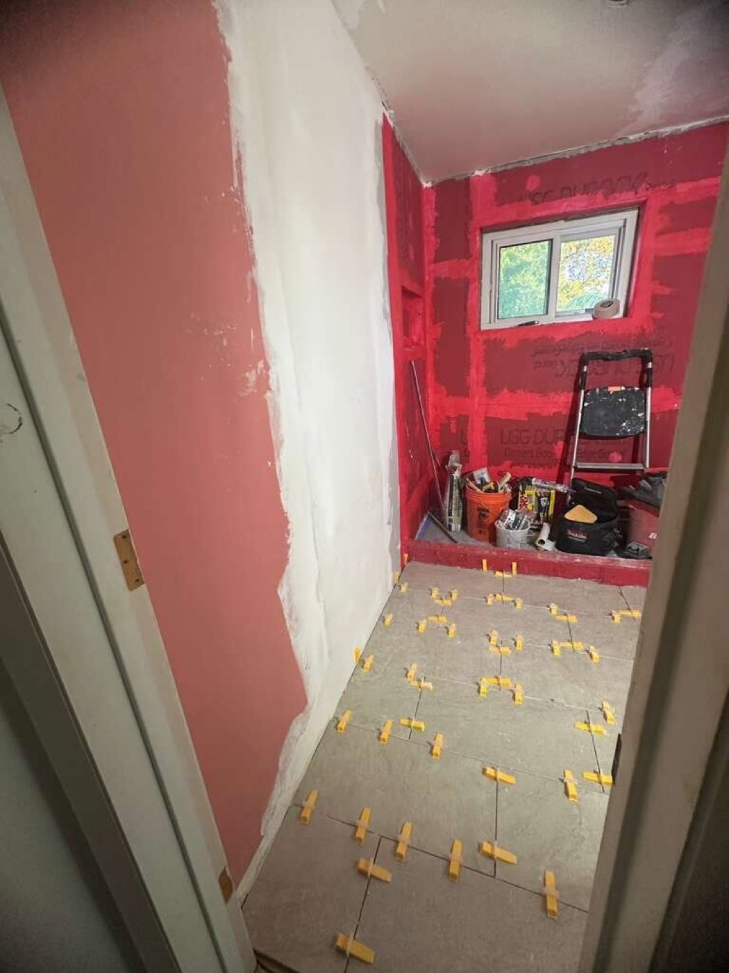 New floor tile going down with leveling clips, the shower wall boarded.