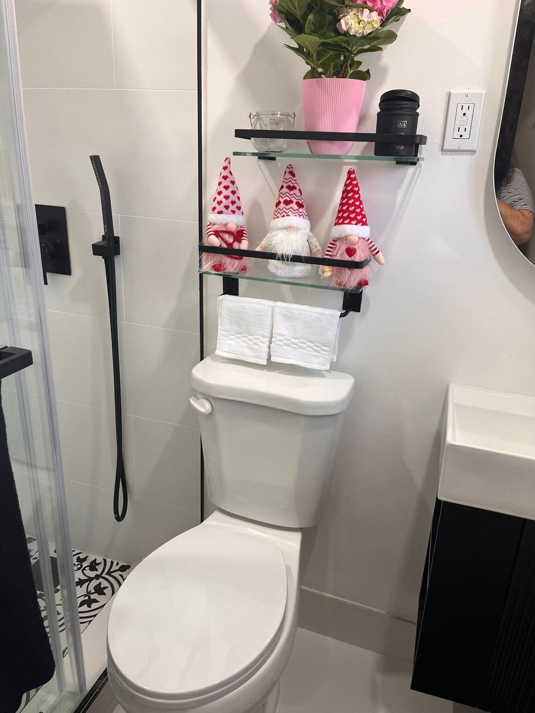 The finished bathroom: white tile, black fixtures and open shelving.