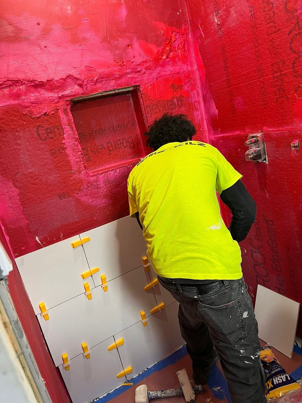 Shower walls coated in red waterproofing, niche framed, tile going on.