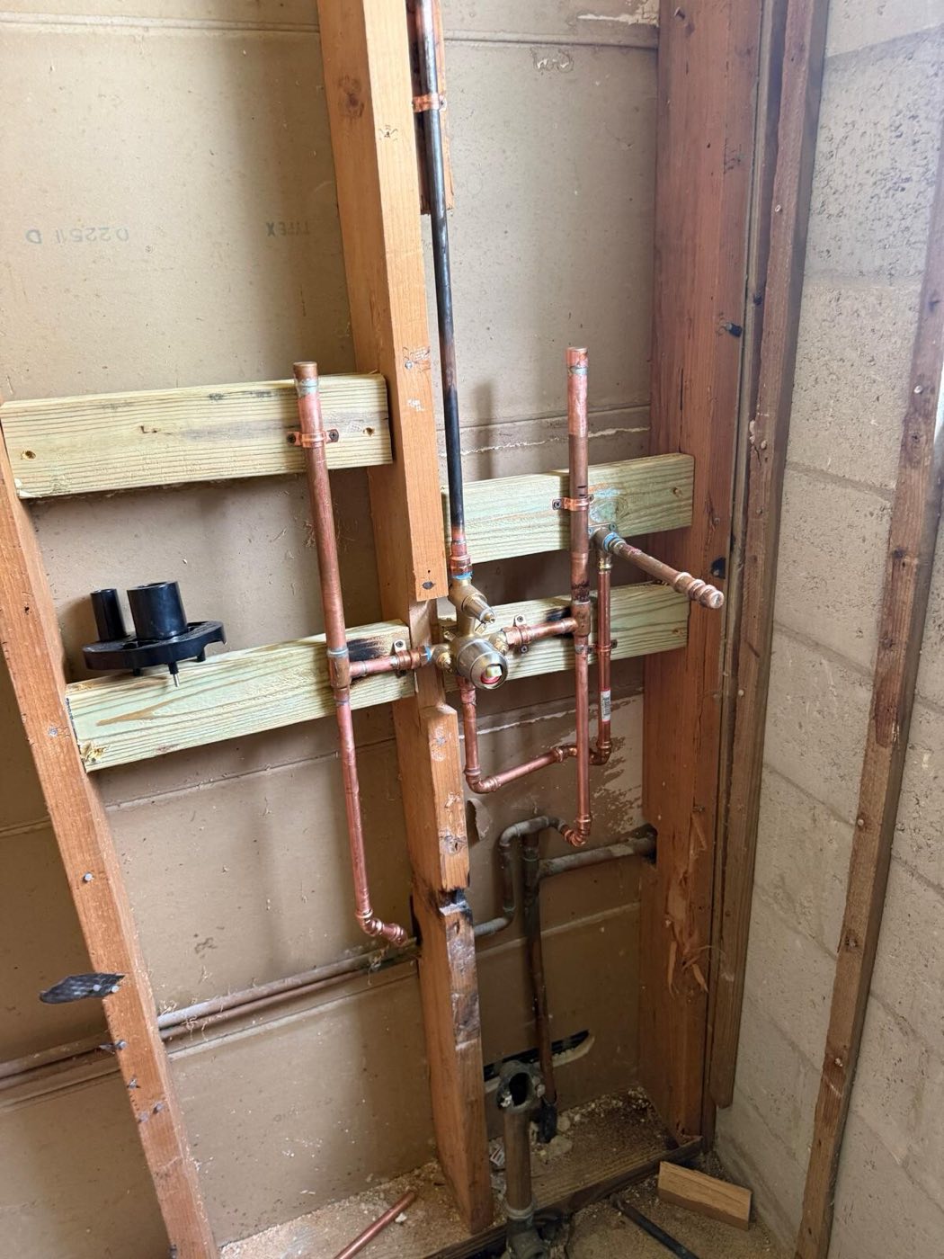 New copper supply lines and valves roughed into the opened wall.