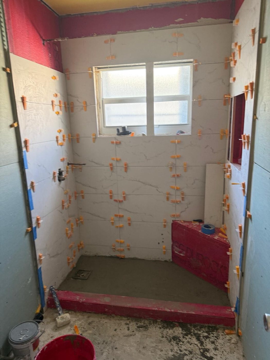 Marble-look tile going up, spacers holding the joints while it cured.