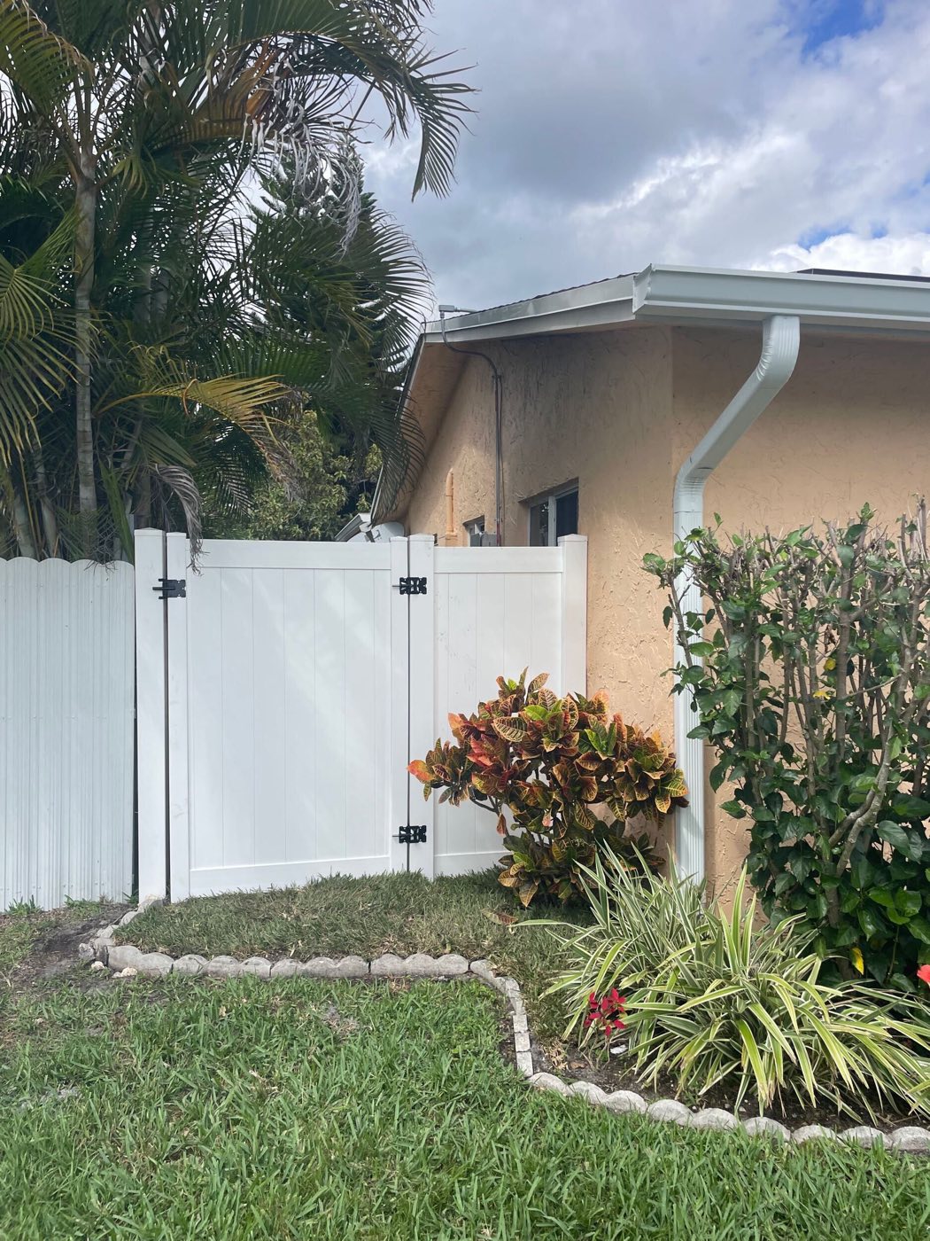 The new white vinyl gate at the side of the house, where a green chain-link gate stood before.