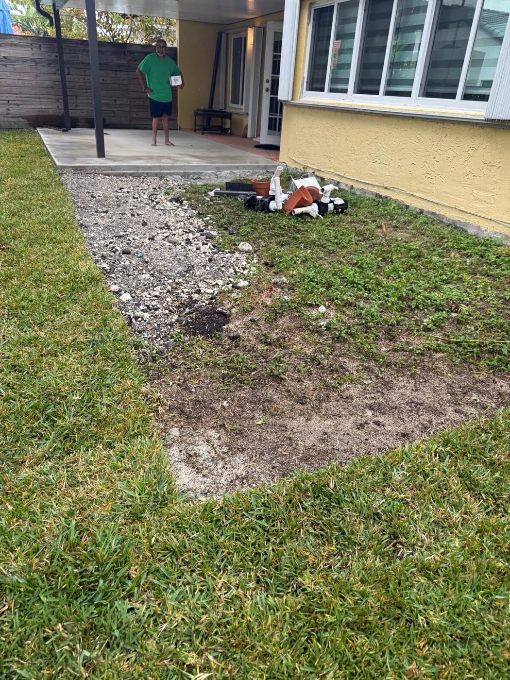 Before: gravel and bare ground meeting the grass line, where the slab now sits.