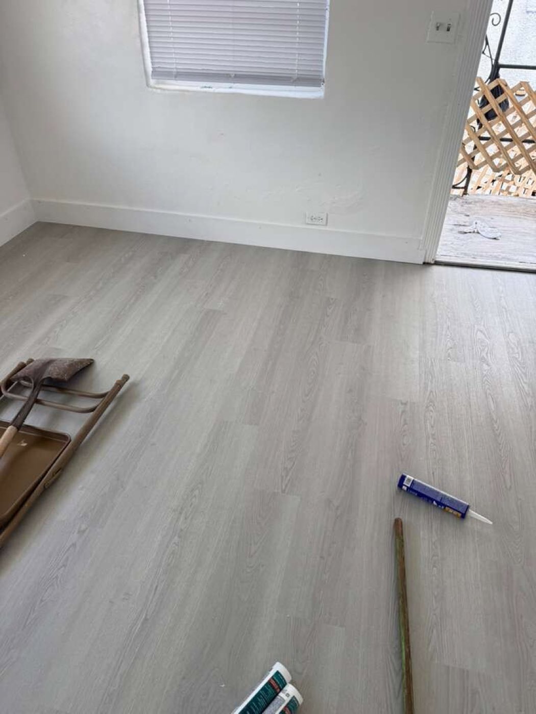 Plank laid to the doorway, blue tape down and baseboard off the wall.