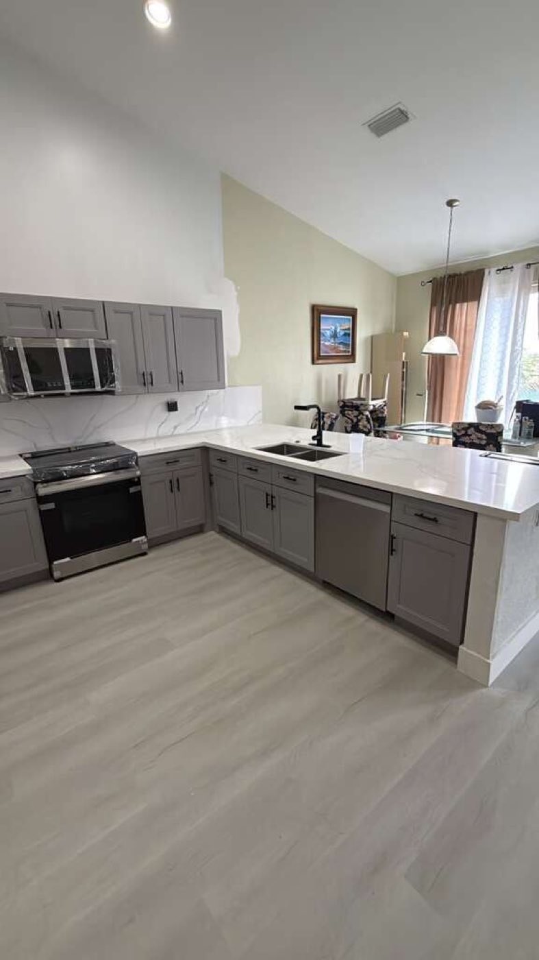 The finished kitchen with its peninsula, range wall and new plank floor.