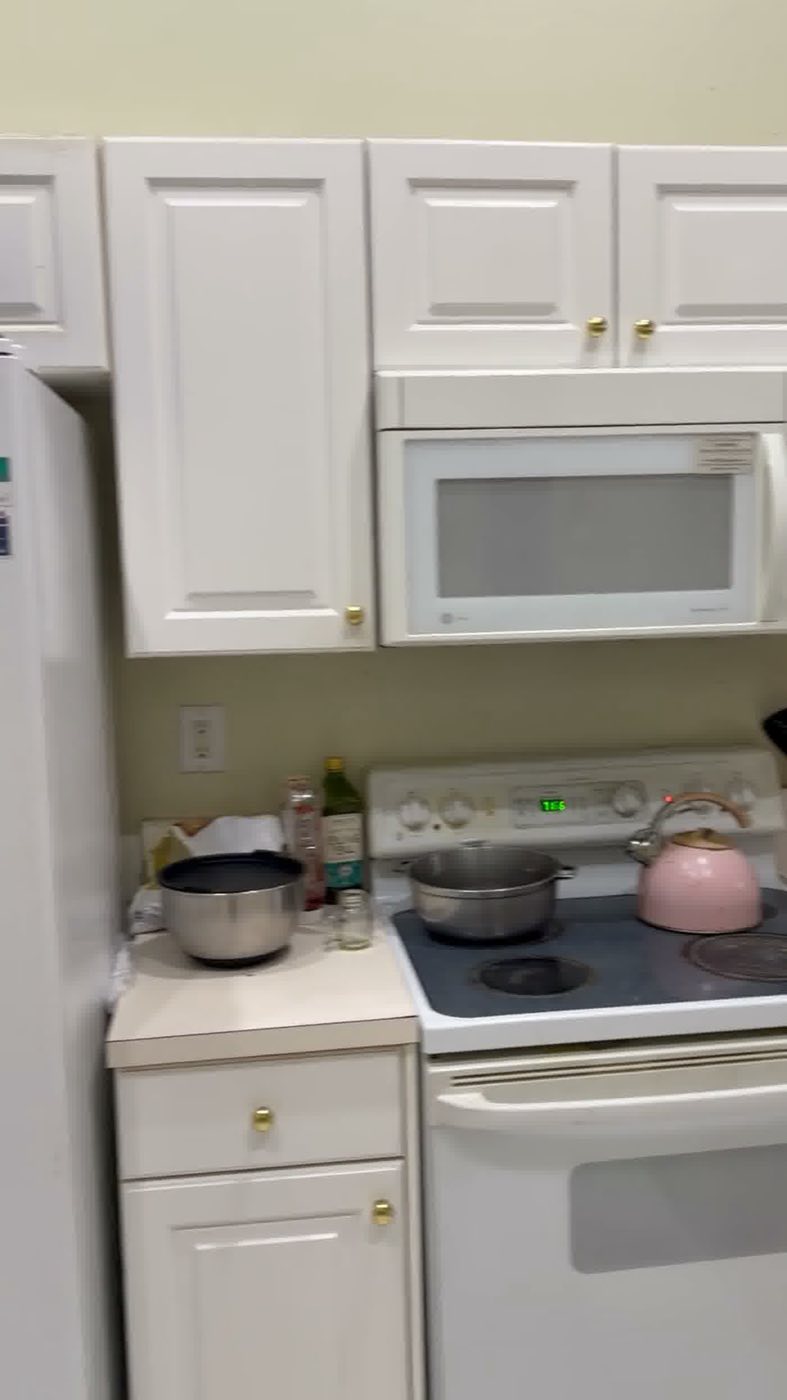 Before: white raised-panel cabinets, a white range and microwave.