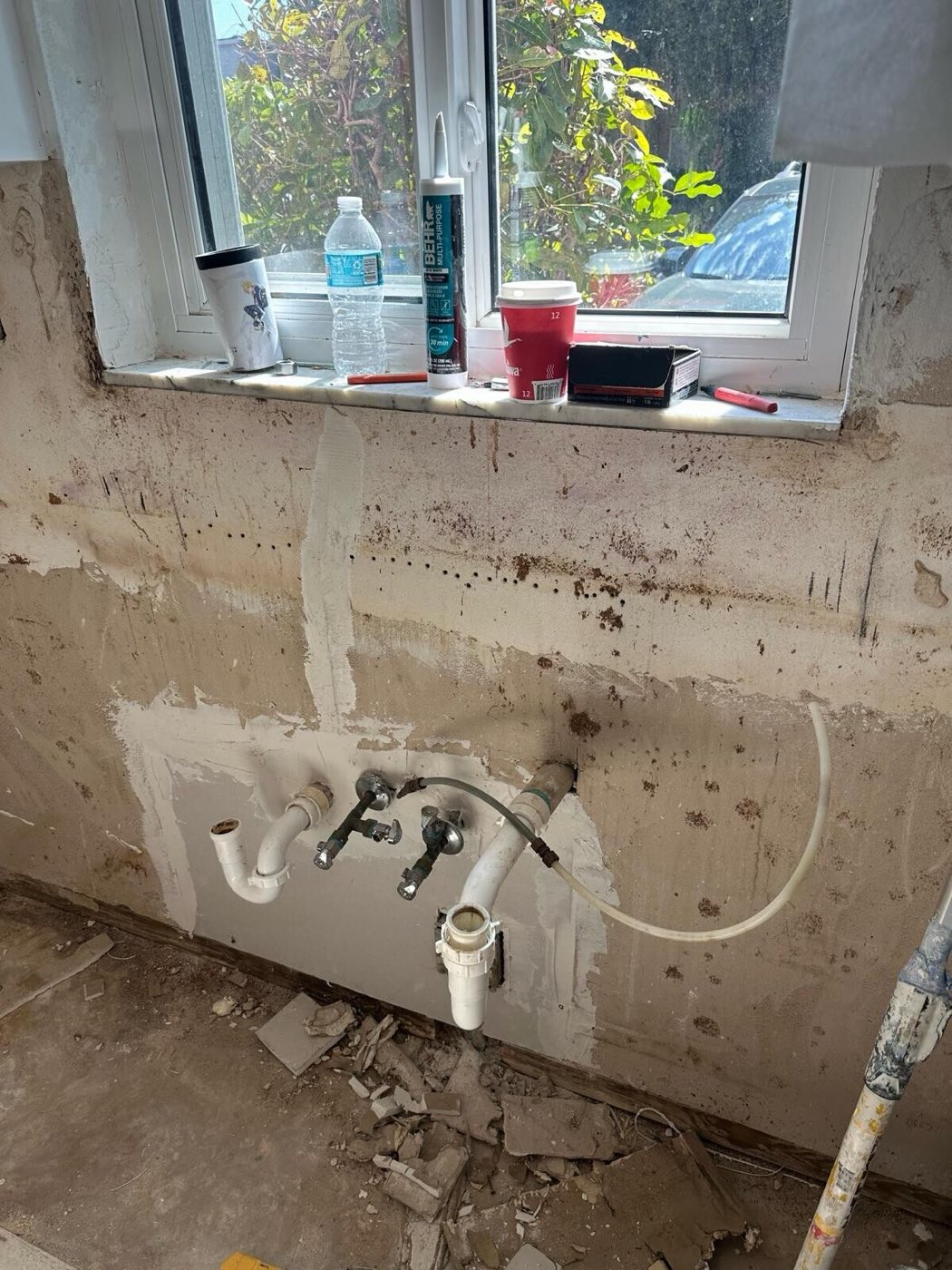 The wall under the window opened up, old plumbing stubs exposed.