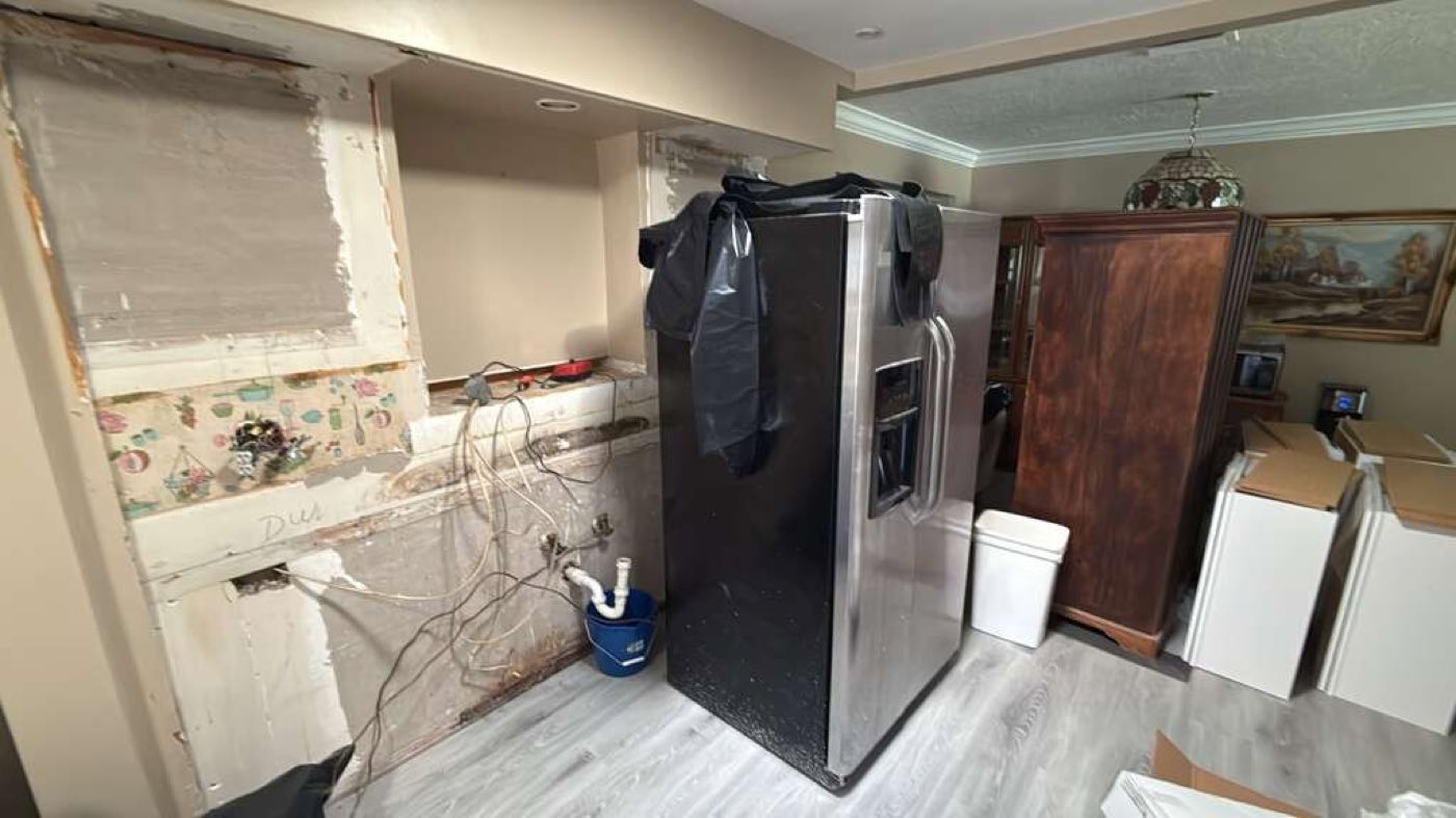 Before: original kitchen mid-demolition: floral wallpaper, cabinets pulled, framing showing.