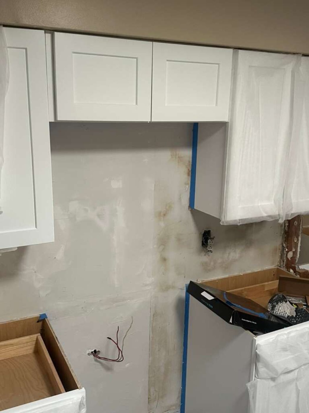 White wall cabinets going in, every edge blue-taped.