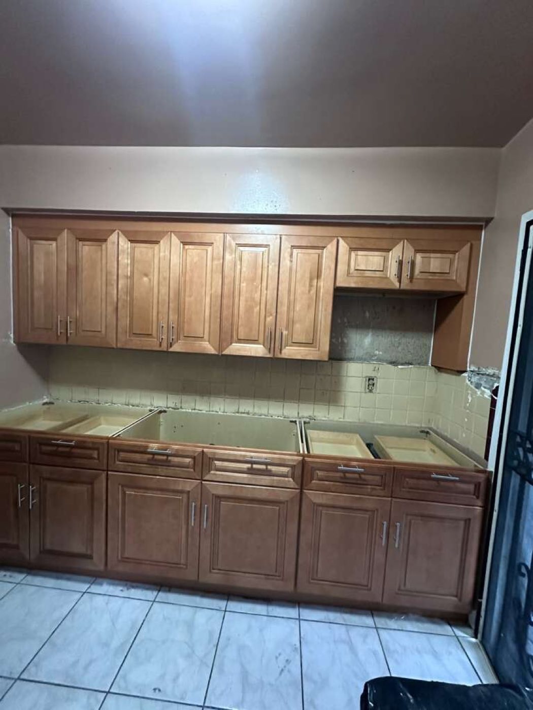 The countertop stripped out, the old beige tile backsplash still up, cabinets left in place.